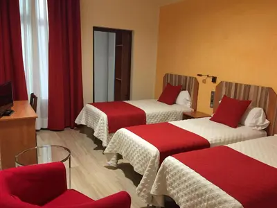a hotel room with three beds and a chair at Alba Hotel in Barcelona