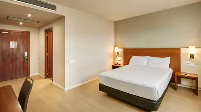 a bedroom with a bed and a table and a chair at Sercotel Ciutat de Montcada in Montcada i Reixac