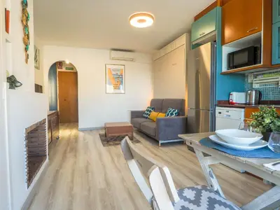 a kitchen and living room with a table and a couch at The Beach Studio by Hello Homes Sitges in Sitges