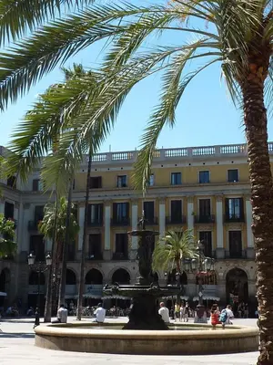 a building with palm trees in front of a fountain at Roma Reial in Barcelona