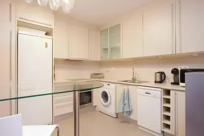 a kitchen with white cabinets and a washer and dryer at Vale Beach in Barcelona