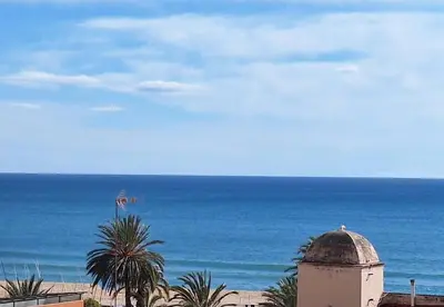 a view of the ocean with a building and palm trees at Marina Vila House, Masnou in Masnou