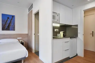 a kitchen with white cabinets and a bed in a room at Aparthotel Augusta in Barcelona
