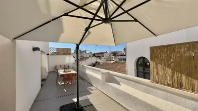 a balcony with a table and an umbrella at Penthouse in Historic Sitges -Big Terrace & Private Solarium in Sitges