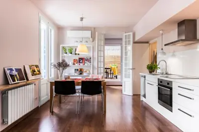 a kitchen with white cabinets and a table and chairs at Bed&BCN Diagonal 2 in Barcelona
