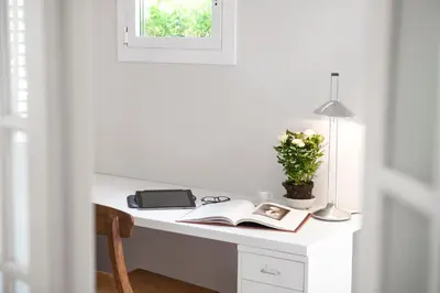 a white desk with a book and a lamp at Bed&BCN Diagonal 2 in Barcelona
