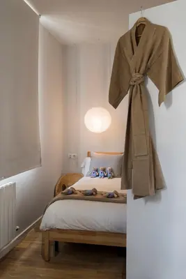 a bedroom with a bed with a robe hanging on the wall at Bed&BCN Diagonal 5 in Barcelona