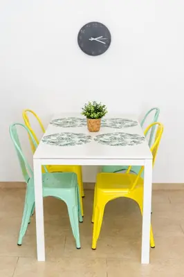 a table with colorful chairs and a clock on the wall at oasis en el centro de manresa in Manresa