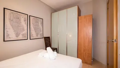 a bedroom with a white bed and a wooden cabinet at BeBarceloner Gracia Apartments- 1 bedroom in Barcelona