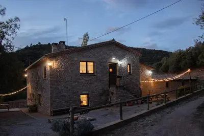 a stone house with lights on it at night at Mas Cal Gira in Moià