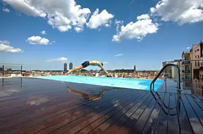 a man diving into a swimming pool on a rooftop at Grand Hotel Central, Small Luxury Hotels in Barcelona