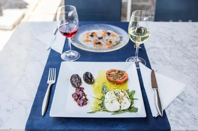 a table with a plate of food and two glasses of wine at Can Fisa Hotel & Apartments in Corbera de Llobregat