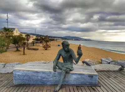 a statue of a man sitting on the beach at CasaBala - Near the beach and Barcelona center in Badalona