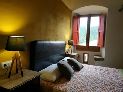 a bedroom with a bed with a black headboard and a window at Mas Can Puig de Fuirosos ONLY ADULTS in La Batlloria