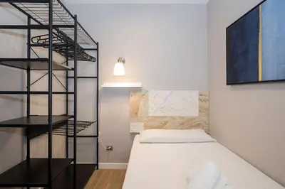 a small bedroom with a bed and a black shelf at BeBarceloner Sant Andreu Apartments - 3 bedrooms with terrace in Barcelona