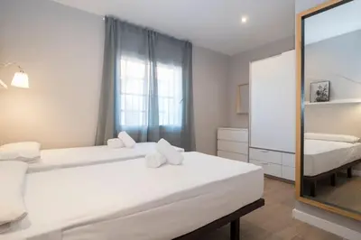 a white bedroom with two beds and a mirror at BeBarceloner Sant Andreu Apartments - 3 bedrooms with terrace in Barcelona