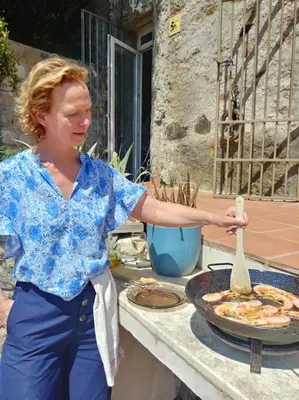 a woman is standing next to a grill with a wooden spoon at Cottage Eco-Friendly Barcelona country side in La Garriga