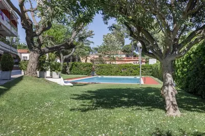 a swimming pool in a yard with trees and grass at HHBCN Beach Apartment Castelldefels #3 in Castelldefels
