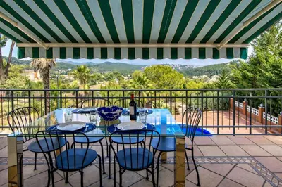 a table with chairs and a bottle of wine on a patio at Catalunya Casas Elegant Mountain Villa just 30km to Barcelona in Corbera de Llobregat