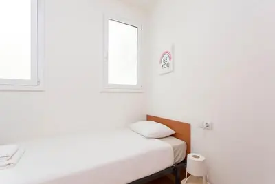 a small room with a bed and two windows at The Collection Barcelona - 3BD only for Families in Poblenou next to the beach! in Barcelona