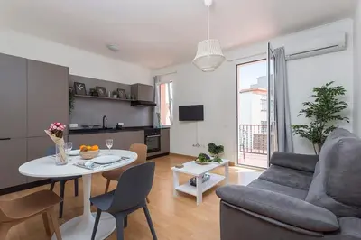a living room with a table and a couch and a kitchen at The Collection Barcelona - 3BD only for Families in Poblenou next to the beach! in Barcelona