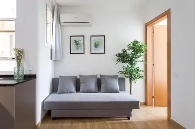 a couch in a living room with two plants at The Collection Barcelona - Sunny 3BD only for Families in Poblenou next to the sea! in Barcelona