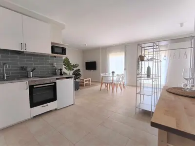 a kitchen with white cabinets and a living room at Mazi Apartments Havana in Mataró