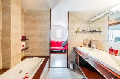 a bathroom with two sinks and a tub and a red chair at Winahost Casa familiar con piscina in Santa Eulalia de Ronsaná