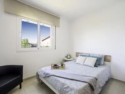 a bedroom with a bed with a chair and a window at Winahost Casa familiar con piscina in Santa Eulalia de Ronsaná