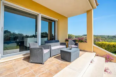 a patio with chairs and a table and large windows at Winahost Casa familiar con piscina in Santa Eulalia de Ronsaná