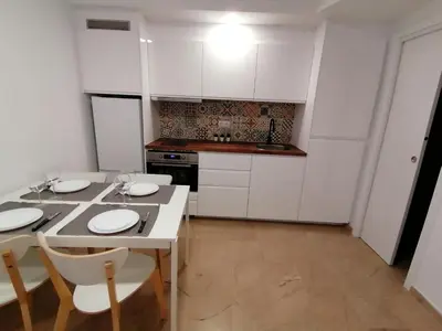 a kitchen with white cabinets and a table and chairs at Piso pl 2A, 20 min Plaza Cataluña in Sant Adria de Besos