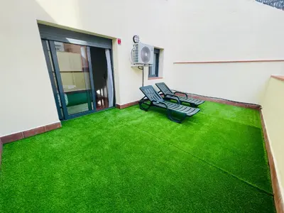 a patio with green grass in a building at Beach Apartment Artigas in Badalona