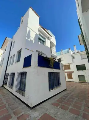 a white building with blue windows on the side of it at Marina Beach Aiguadolç Sitges in Sitges