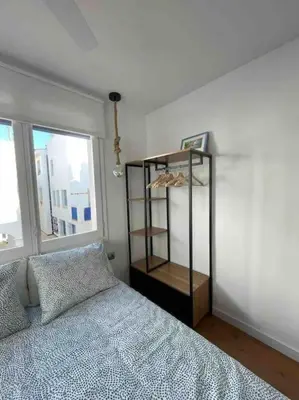 a bedroom with a bed and a shelf next to a window at Marina Beach Aiguadolç Sitges in Sitges