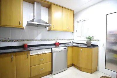 a kitchen with wooden cabinets and a white dishwasher at Nice new apartment only 30min to Barcelona center. in Granollers