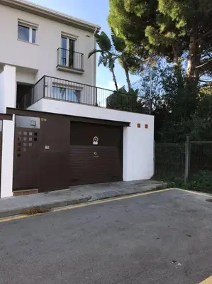 a building with a garage door in front of a house at Casa con piscina Sant Pol de Mar in San Pol de Mar