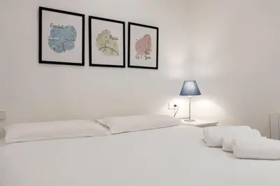 a white bedroom with a large bed with four pictures on the wall at Bebarceloner Poble Nou Apartaments - 2 bedroom in Barcelona