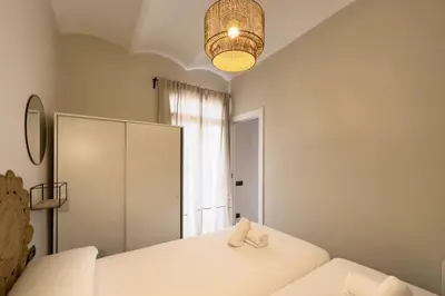 a bedroom with two beds and a chandelier and a window at BeBarceloner Sants Apartments - 2 bedrooms in Barcelona