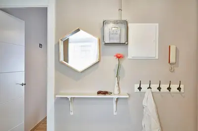 a white bathroom with a shelf and a vase with a flower at BeBarceloner Sants Apartments - 2 bedrooms in Barcelona