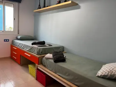 a bedroom with two beds and a desk and a window at Cozy Beach House with Pool & BBQ in Cubelles