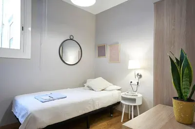 a bedroom with a bed and a table and a mirror at BeBarceloner Eixample Apartments - 2 bedrooms in Barcelona