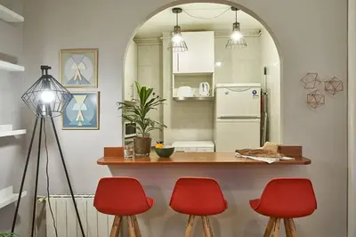 a kitchen with a counter and three red chairs at BeBarceloner Eixample Apartments - 2 bedrooms in Barcelona