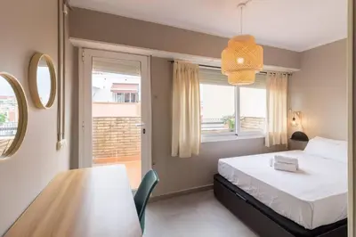 a bedroom with a bed and a table and a window at BeBarceloner Sant Andreu Apartments - Attic with terrace in Barcelona