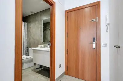 a bathroom with a wooden door and a sink at Urban Flats Vallirana in Barcelona