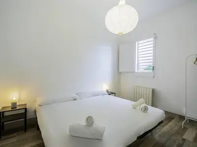 a white bedroom with a white bed and a window at Casa Mediterránea en Badalona in Badalona