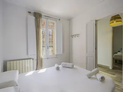 a white bedroom with a large white bed and a mirror at Casa Mediterránea en Badalona in Badalona