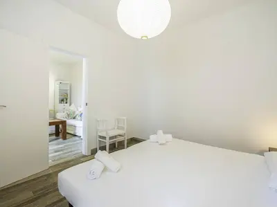 a white bedroom with a bed and a living room at Casa Mediterránea en Badalona in Badalona