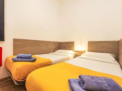 two beds in a room with yellow and white at Apartment Sants-Montjuïc- Avenida Madrid by Interhome in Barcelona