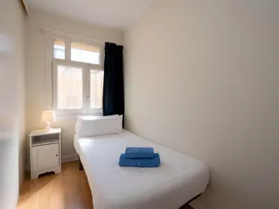 a small bedroom with a white bed and a window at Apartment Sagrada Familia- Rossello by Interhome in Barcelona