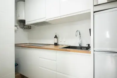 a white kitchen with a sink and white cabinets at Ático en Calella a 7 minutos de la playa in Calella